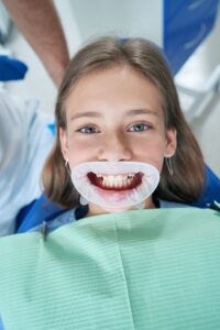 Young patient with a dental mouth opener, prepared for a medical examination, emphasizing our thorough dental check-ups.