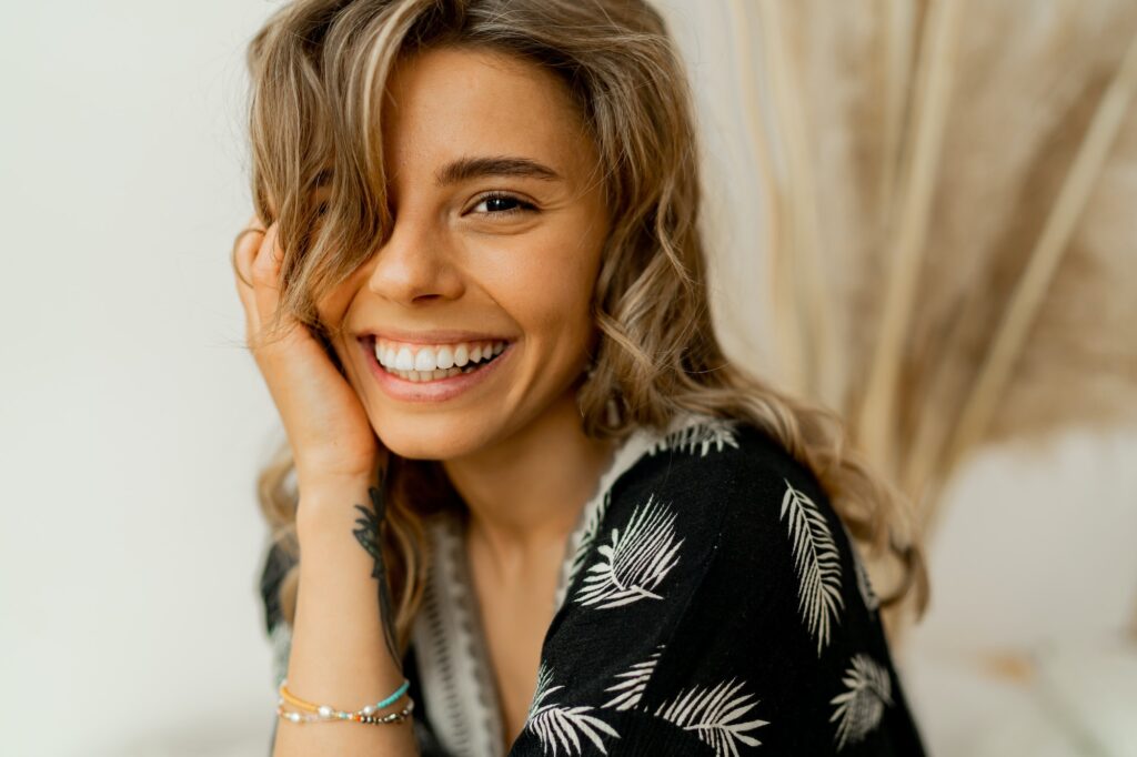 Woman with a perfect smile, dressed in a stylish boho outfit, exemplifying confidence and dental health.