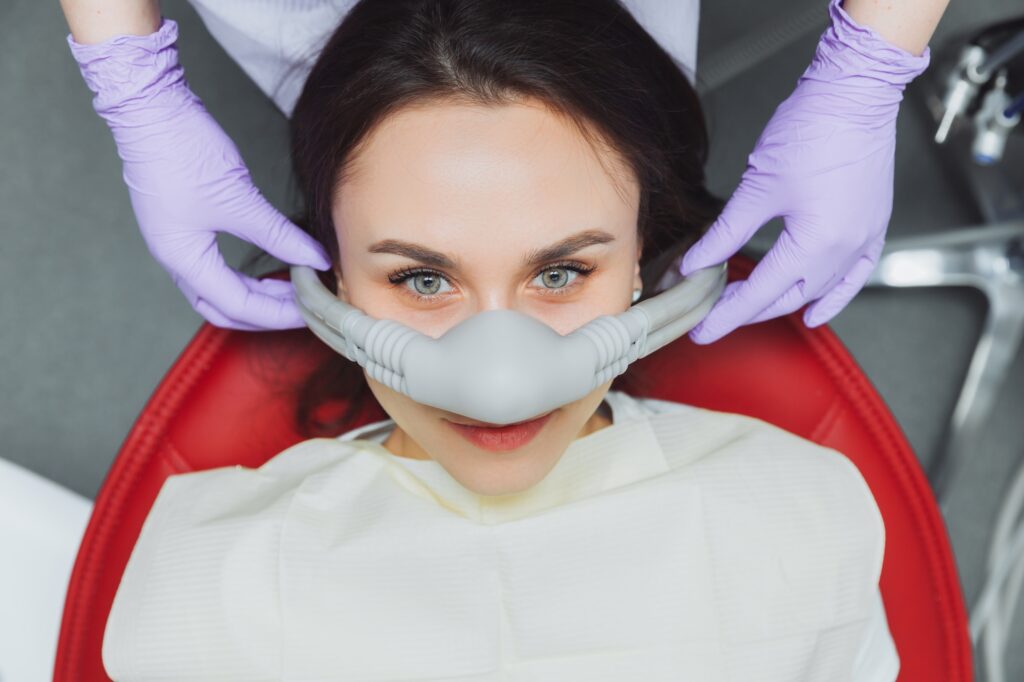 A dentist at Creve Coeur Family & Sedation Dentistry gently placing a nitrous oxide mask on a patient to provide stress-free and comfortable sedation dentistry services in Creve Coeur, MO.